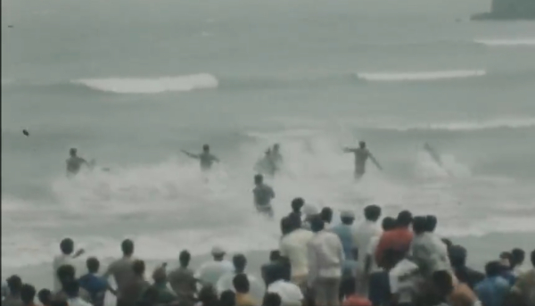 Swimmers running into the sea whiles the crowd cheered them on