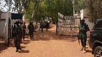 Nigerian soldiers and police officers stand at the entrance of a college in Kaduna state