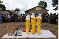 Red Cross workers don PPE prior to burying a three-year-old boy suspected of dying from Ebola