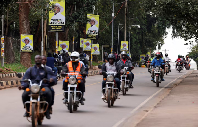 Motorcycle taxis ride past campaign posters of Uganda's President and leader of the ruling NRM party