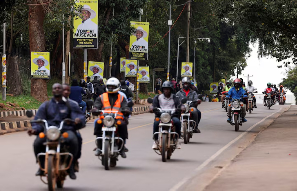 Motorcycle taxis ride past campaign posters of Uganda's President and leader of the ruling NRM party