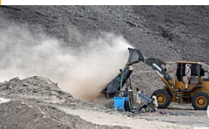 A front-loader deposits dirt and crushed rock into a processing machine