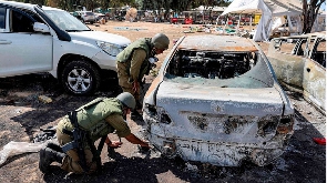 Soldiers search the remains of a torched vehicle for forensic evidence