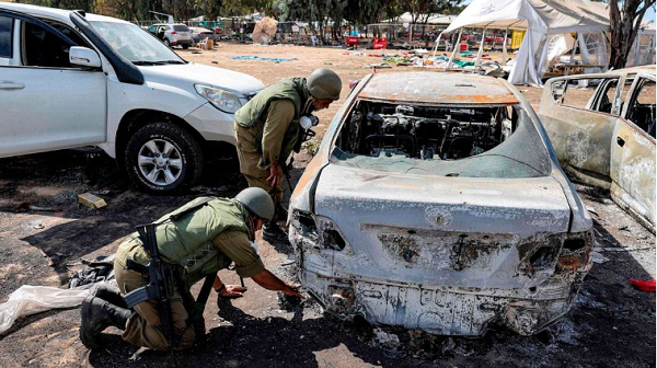 Soldiers search the remains of a torched vehicle for forensic evidence