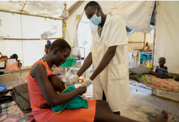 Nyayiar Kuol holds her severely malnourished 1-year-old daughter as she is attended by a doctor