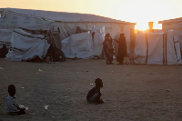 Sudanese refugee children from el-Fasher play as the sun sets over the Tine transit refugee camp