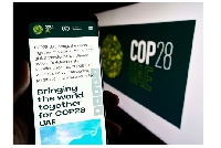 Person holding cellphone with web page of UN climate change conference COP28 on screen
