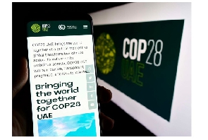 Person holding cellphone with web page of UN climate change conference COP28 on screen