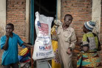 A Burundian official talks to Congolese refugees while inspecting rice from the last US aid shipment