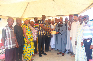 A member of the group presenting the money to the chairman of the disaster committee