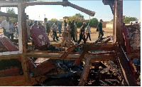 People walk past a destroyed vehicle after shelling by the Rapid Support Forces in Omdurman, Sudan