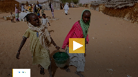 Sudanese refugee girls carry water supplies near a polling station in the refugee camp of Zamzam