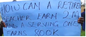 One of the humanities teachers holds a protest poster during their meeting in Masaka City on June 10