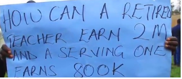 One of the humanities teachers holds a protest poster during their meeting in Masaka City on June 10