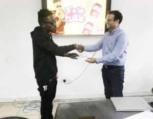 Shatta Wale in a handshake with a representative of Boss Baker Beef Roll