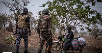 A police officer and a soldier from Benin stop a motorcyclist at a checkpoint outside Porga, Benin