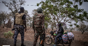 A police officer and a soldier from Benin stop a motorcyclist at a checkpoint outside Porga, Benin