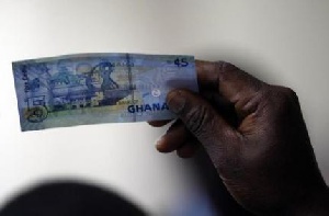 Man holds up 5 cedi note