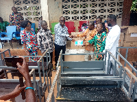 The MP, Bismarck Tetteh Nyarko (left) presenting some desks to the beneficiary schools