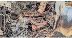 People gather around the charred remains of a burned vehicle after a deadly attack in Komanda, Ituri