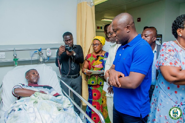 Mayor Sowah (in blue) visits a patient in his ward at the Greater Accra Regional Hospital