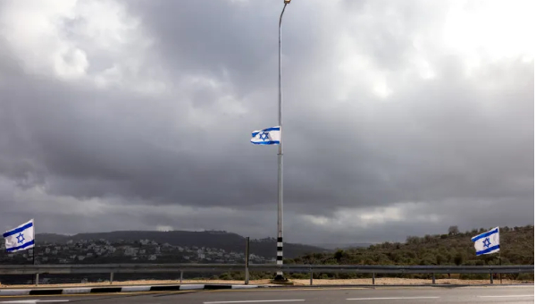 Israeli flags flutter at the entrance to an Israeli settlement in the occupied West Bank