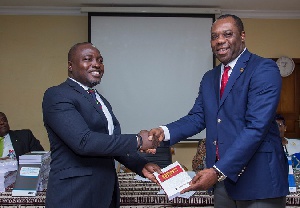 Mr Ebenezer Akyeampong of Heritage Bank presenting a copy of the book to Education Minister
