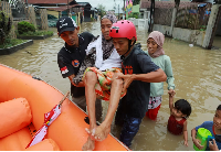 Rescuers evacuate an elderly woman from an area flooded by heavy rains in Deli Serdang