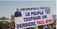 Supporters of Paul Biya, seeking an eighth term, hold a sign during the launch of his campaign