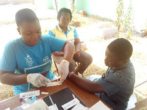 An official getting ready to take a blood sample of an inhabitant of Ejisu