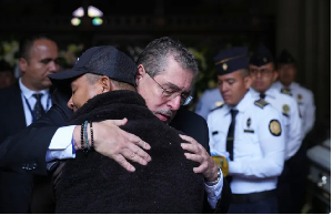 Guatemalan President Bernardo Arevalo comforts the relative of one of the police officers killed