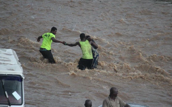 Men trying to save a woman who's been stranded in the floods