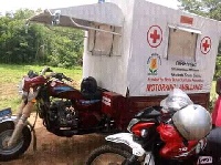 A tricycle branded and being used as an ambulance