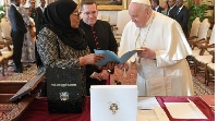 Tanzania's President Samia Suluhu Hassan (L) and Pope Francis exchange a document in the Vatican