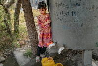 A girl fills canisters of water from a tap with non-potable water to use at home