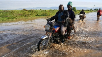 People ride through flood waters following heavy rains in Ahero, Western Kenya, March 24, 2026