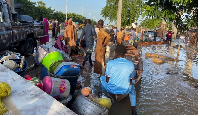 Flood victims stand beside their belongings offloaded from a canoe that helped them move to safety