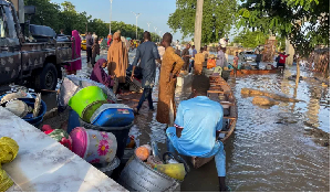 Flood victims stand beside their belongings offloaded from a canoe that helped them move to safety