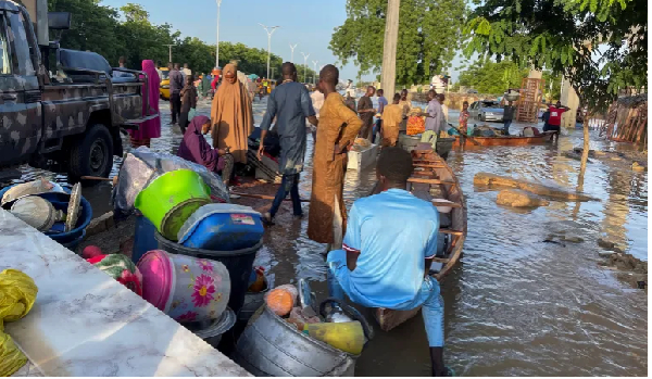 Flood victims stand beside their belongings offloaded from a canoe that helped them move to safety