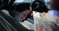 Driver hands over GHC50.00 to a person.     File photo.