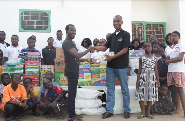 CEO of Origin8, William Ansah (R) presenting the items to Moses Lamptey, a manager at the orphanage