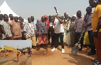 Commey, with pick axe performing the ceremonial ground breaking, while the other dignitaries look on