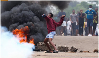 A protester in Maputo throws a stone during a strike called by presidential candidate