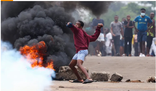 A protester in Maputo throws a stone during a strike called by presidential candidate