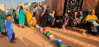 Residents wait to collect food in containers from a soup kitchen in Sudan on March 11, 2024.
