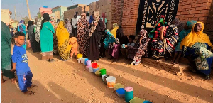 Residents wait to collect food in containers from a soup kitchen in Sudan on March 11, 2024.