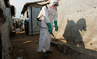 A health worker in full personal protective equipment (PPE) is seen disinfecting an area
