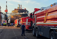 Firefighters and crews gather near a repair cargo ship after it caught fire