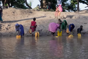Residents move through floodwaters on a street in the town of Beledweyne