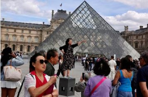 Tourists at the Louvre pose for pictures at the Paris Louvre Museum